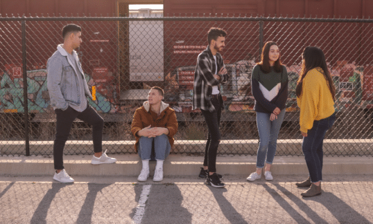 Teenagers standing against a fence