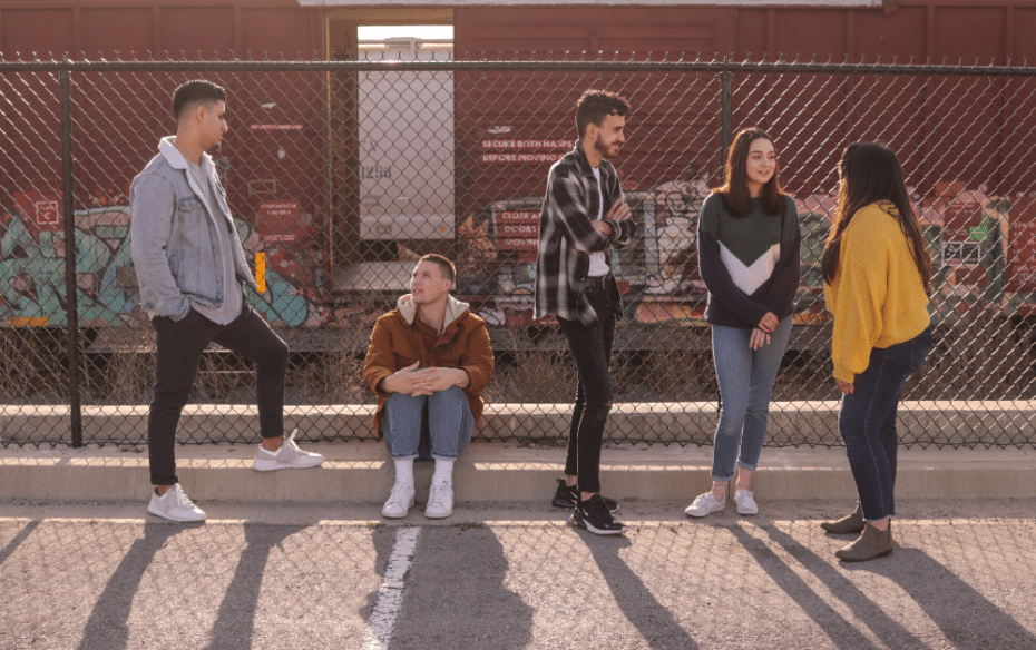 Teenagers standing against a fence