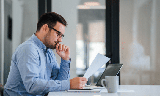 A man sitting at a desk considering a harassment investigation document