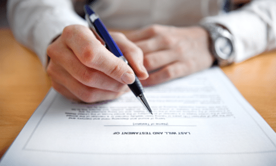 An estate lawyer holds a pen above a will