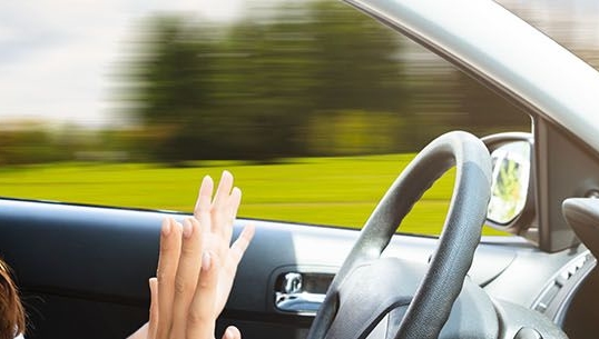 Person behind the wheel of an autonomous vehicle with their hands off the wheel.