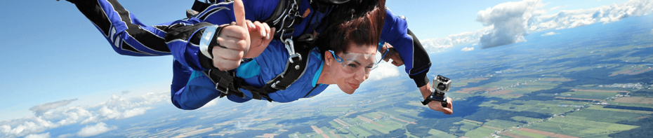Woman sky diving over green fields.
