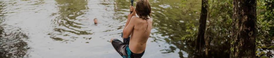 Young boy swings on rope into jump into a lake