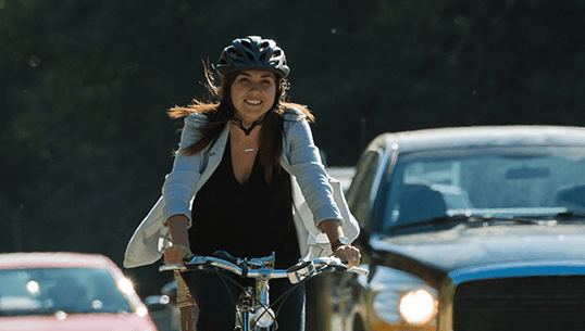 Woman on bike along busy street