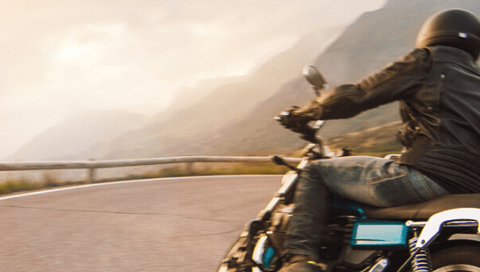 A man on a motorbike driving down a windy road