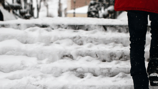 A woman walks up icy, slippery stairs