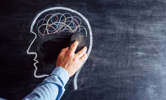 hand erasing the brain from a head shape drawn on blackboard