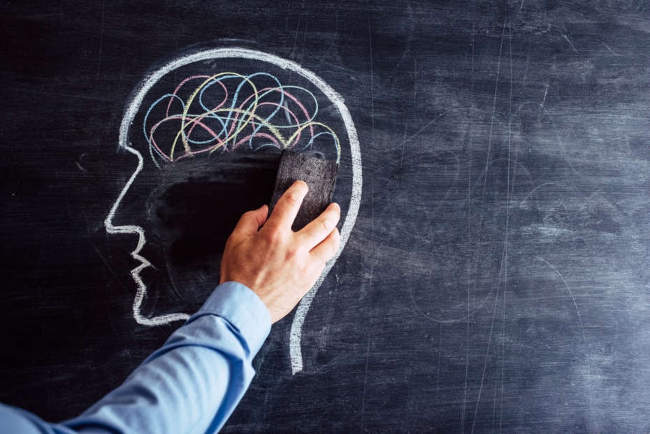 hand erasing the brain from a head shape drawn on blackboard