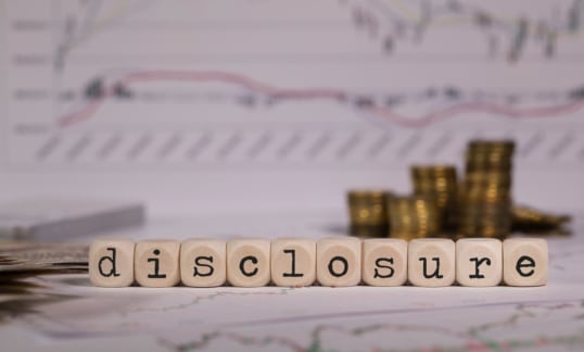 Word DISCLOSURE composed of wooden letters. Stacks of coins in the background. Closeup