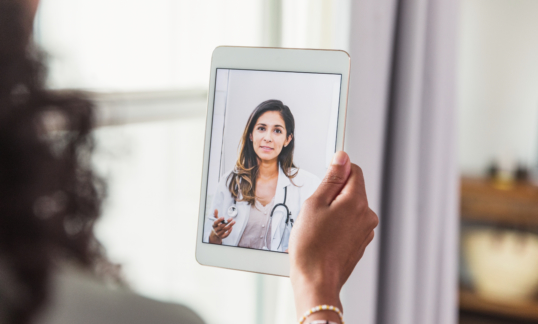 A female doctor offers patient advice during virtual healthcare appointment.