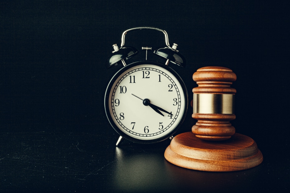 Wooden judge hammer with alarm clock on black background