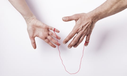 A man and woman with a thin red string tied to each of their hands.
