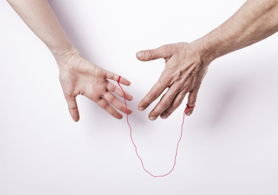 A man and woman with a thin red string tied to each of their hands.