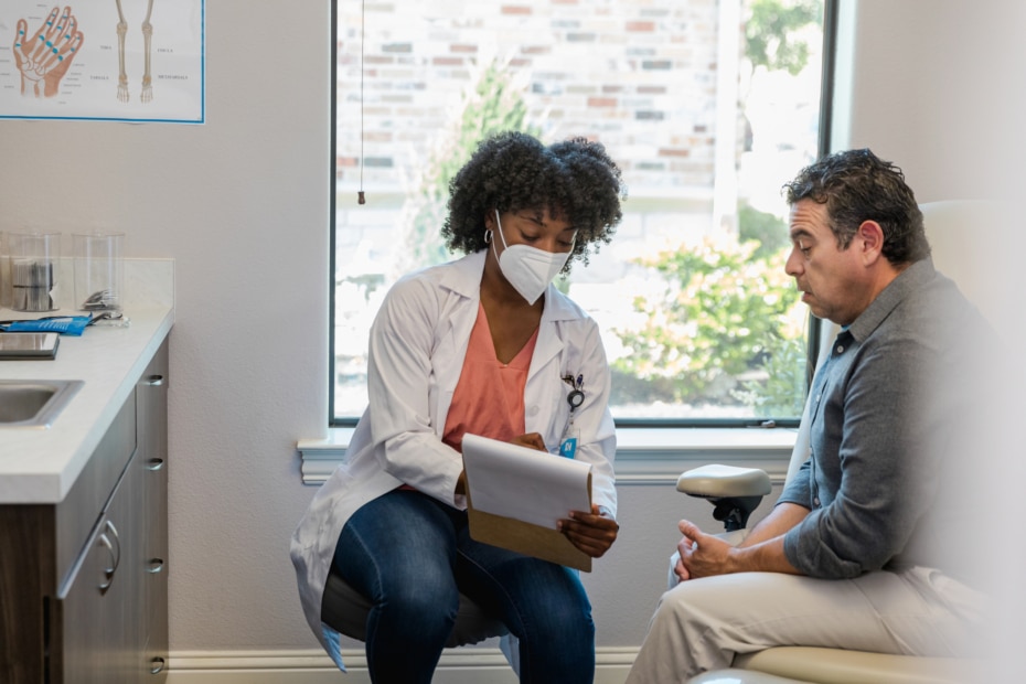 Doctor and man looking at clipboard and talking.