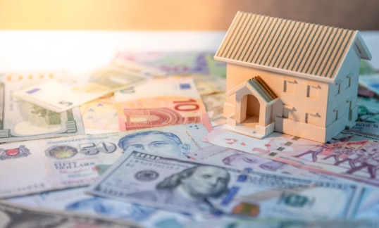 Wooden house model on a floor of money